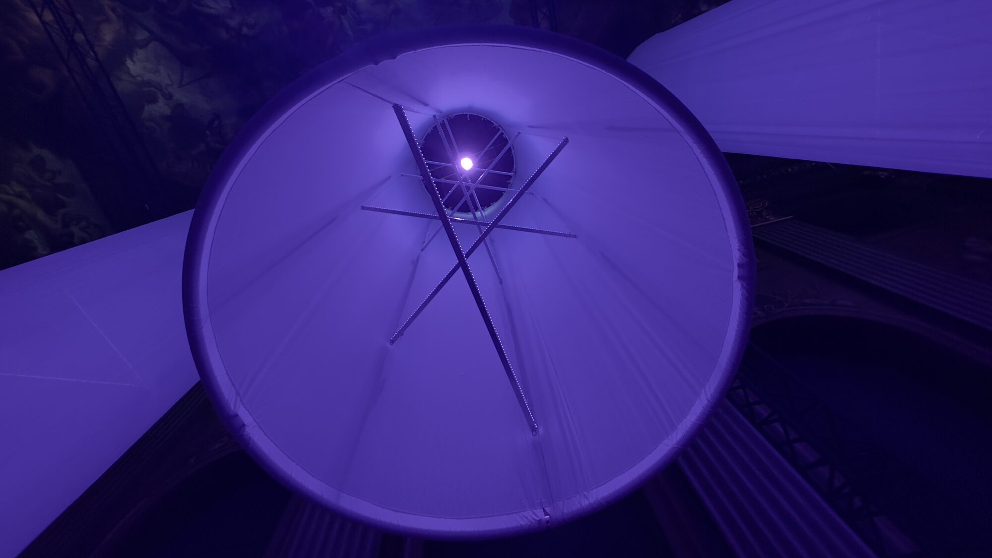 Colonne lumineuse cylindrique dans le Painted Hall, vue d’en bas, baignée de violet profond